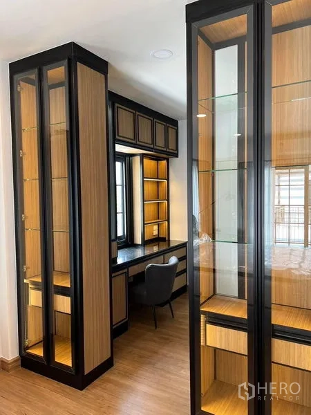 Detached House for rent in Bang Phli, Samut Prakan - Walk-in dressing area featuring glass display cabinets, vanity desk and warm wood flooring.