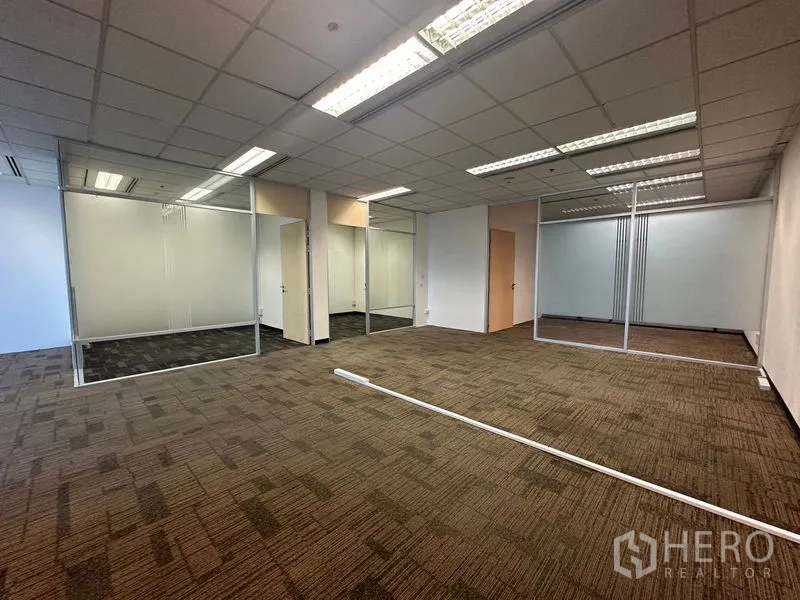 Office Space for rent in Khlong Toei, Bangkok - Open-plan workspace with glass-partitioned rooms and grid ceiling lighting.