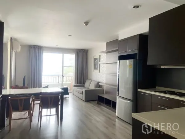 Condominium for rent in Watthana, Bangkok - View from the kitchen toward a bright living area with sofa and balcony at the far end.