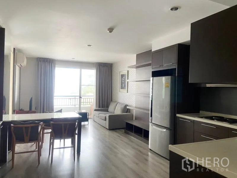Condominium for rent in Watthana, Bangkok - View from the kitchen toward a bright living area with sofa and balcony at the far end.