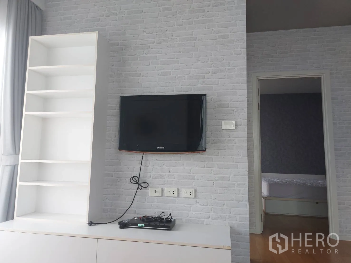 คอนโด ให้เช่าในWatthana, Bangkok - ชั้นวางของและทีวีติดผนังลายอิฐ ข้างประตูเข้าห้องนอน