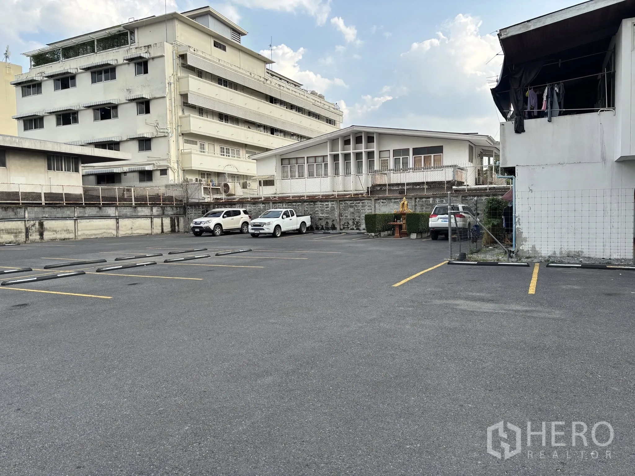 Land for rent in Sathon, Bangkok - Paved yard with parking lines, perimeter wall, and adjacent buildings in an urban setting.