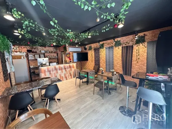 零售空间 出租在Watthana, Bangkok - 咖啡馆风格室内：砖墙、吧台与多样座位，天花绿植装饰