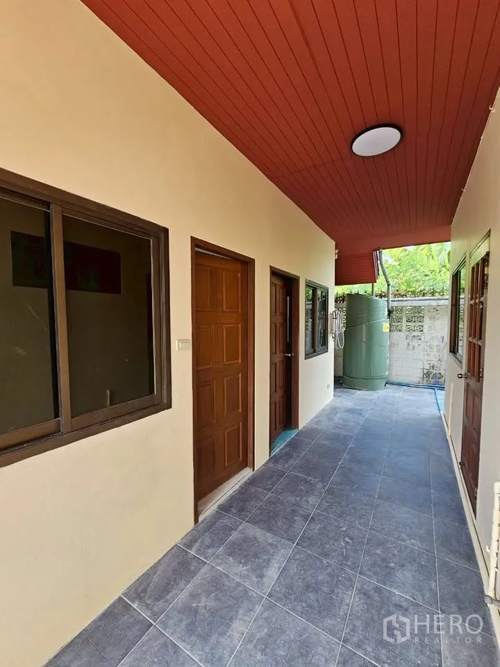 สำนักงานที่บ้าน for rent in Wang Thonglang, Bangkok - โถงทางเดินหลังบ้านใต้ฝ้าแดง มีประตูหลายบานและแทงก์น้ำท้ายทาง