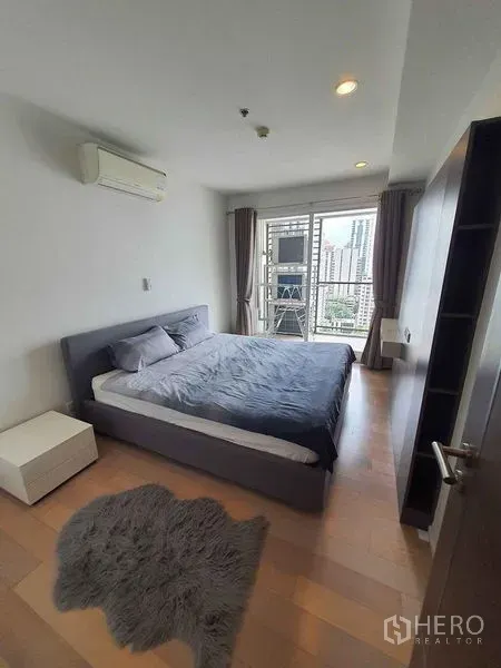 Condominium for rent in Watthana, Bangkok - Second bedroom with balcony door, air conditioner and skyline view over Sukhumvit.