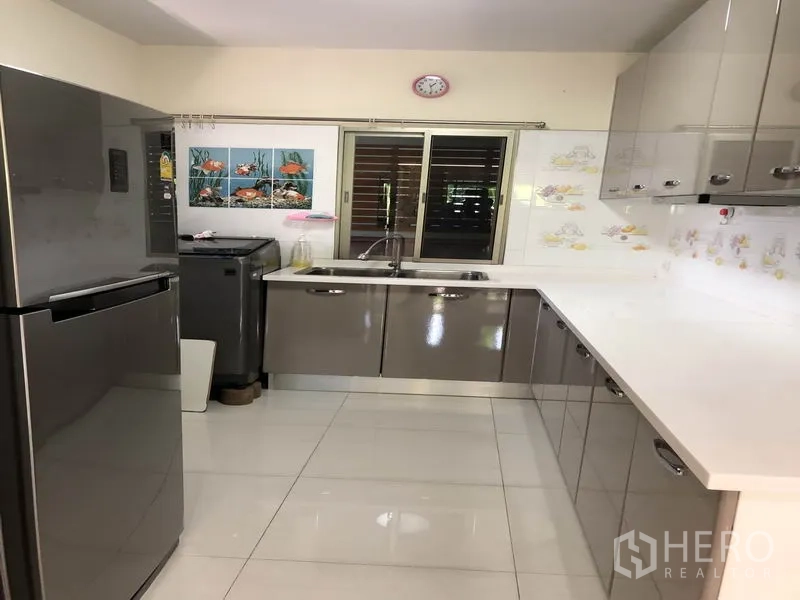 บ้าน ให้เช่าในSuan Luang, Bangkok - ครัวรูปตัว U ตู้ลามิเนตสีเงา เคาน์เตอร์สีขาว และหน้าต่างรับแสง