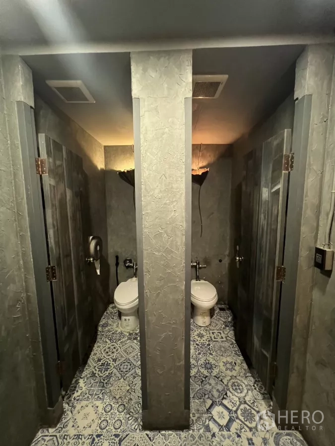 零售空间 出租 - 卫生间隔间，花纹地砖与肌理混凝土墙面。