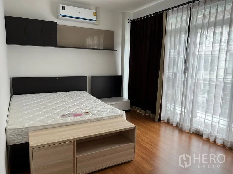 ทาวน์เฮาส์ ให้เช่าในSaphan Sung, Bangkok - ห้องนอนมุมมีประตูกระจกสูงถึงพื้น ม่านโปร่ง และเตียงควีนไซซ์