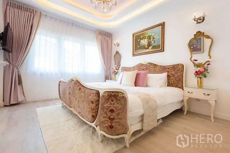 Townhouse for rent in Lat Phrao, Bangkok - Elegant bedroom with vintage upholstered bed, chandelier and soft pink drapes.