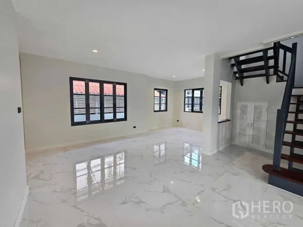 Detached House for sale in Thanyaburi, Pathum Thani - Bright living area with white marble-look flooring and black-framed windows.