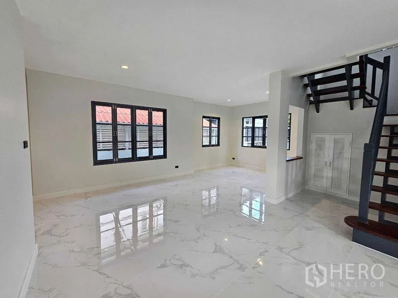 Detached House for sale in Thanyaburi, Pathum Thani - Bright living area with white marble-look flooring and black-framed windows.