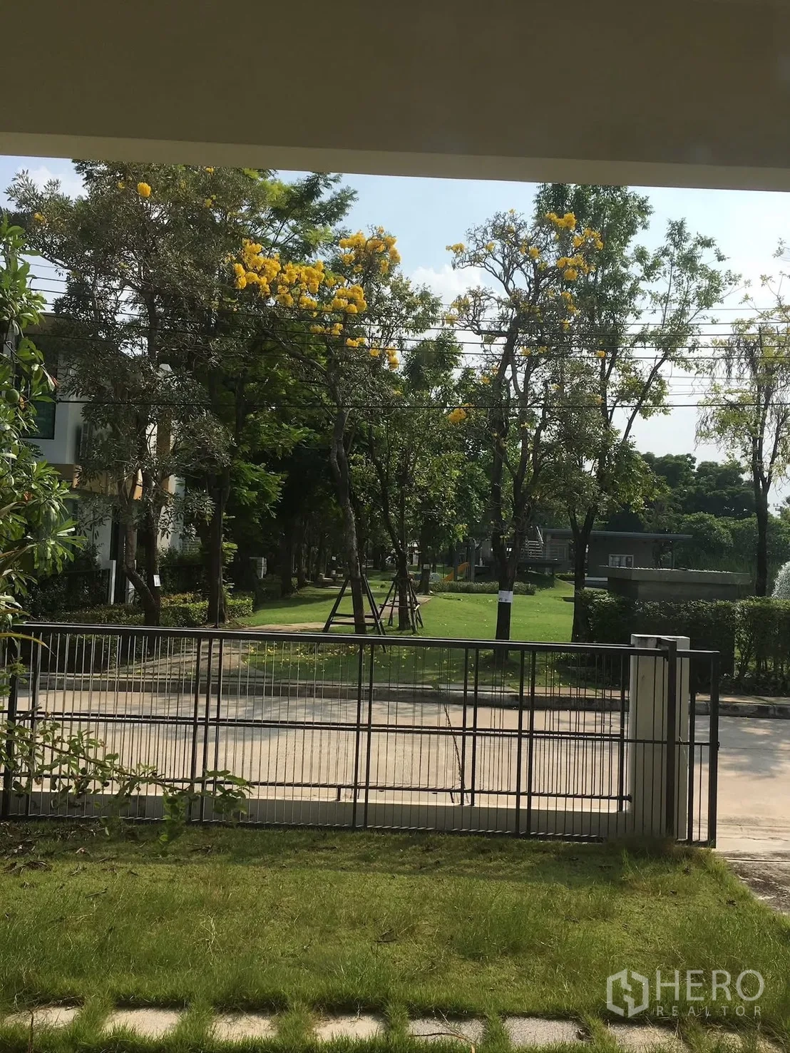 独栋房屋 for rent in Bang Na, Bangkok - 前庭与围栏，可眺望绿地与开花树木。