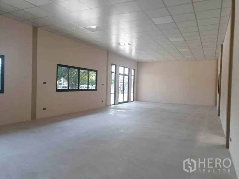 Warehouse for rent in Chachoengsao - Bright office-style room with tiled ceiling, large windows and glass doors inside a warehouse complex.