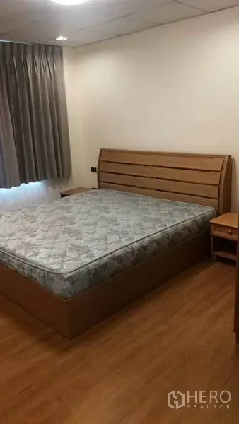 Townhouse for rent in Khlong Toei, Bangkok - Cozy bedroom with wooden bed frame, bedside tables and blackout curtains.