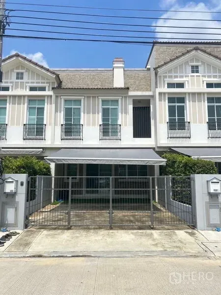 ทาวน์เฮาส์ ให้เช่า - ด้านหน้าทาวน์เฮ้าส์ มีกำแพงเหล็กและพื้นที่จอดรถในร่ม.