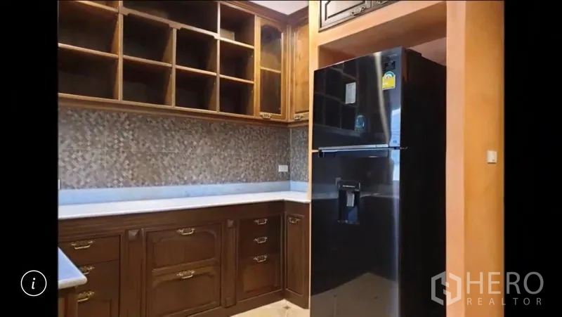 Detached House for rent or sale in Bang Phli, Samut Prakan - Compact pantry with wooden cabinetry, mosaic backsplash and a black refrigerator.