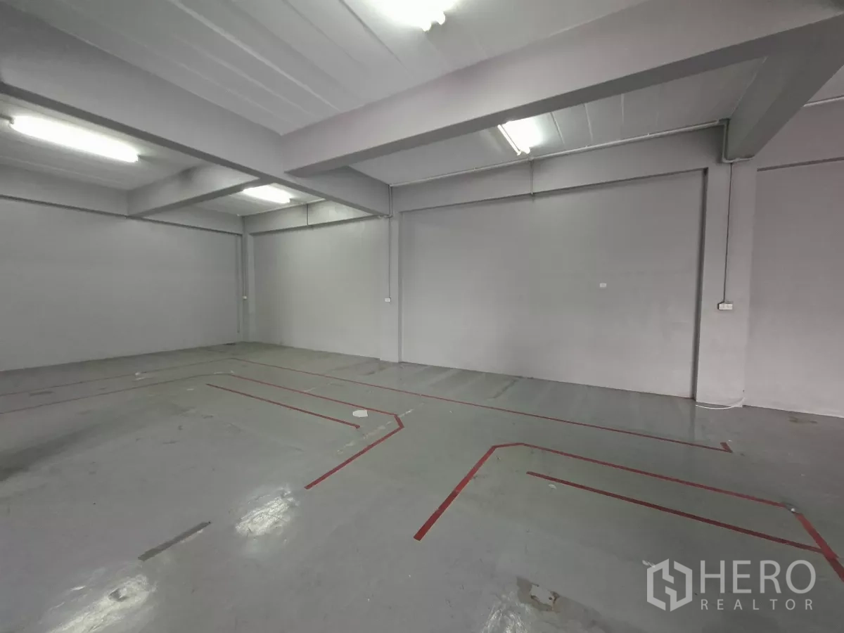 Warehouse for rent in Suan Luang, Bangkok - Upper floor open‑plan area with epoxy floor and marked work zones under bright lighting.
