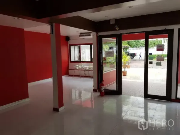พื้นที่ขายปลีก ให้เช่าในWatthana, Bangkok - โถงชั้นล่างพร้อมประตูกระจกบานใหญ่ ผนังสีแดง และพื้นกระเบื้อง