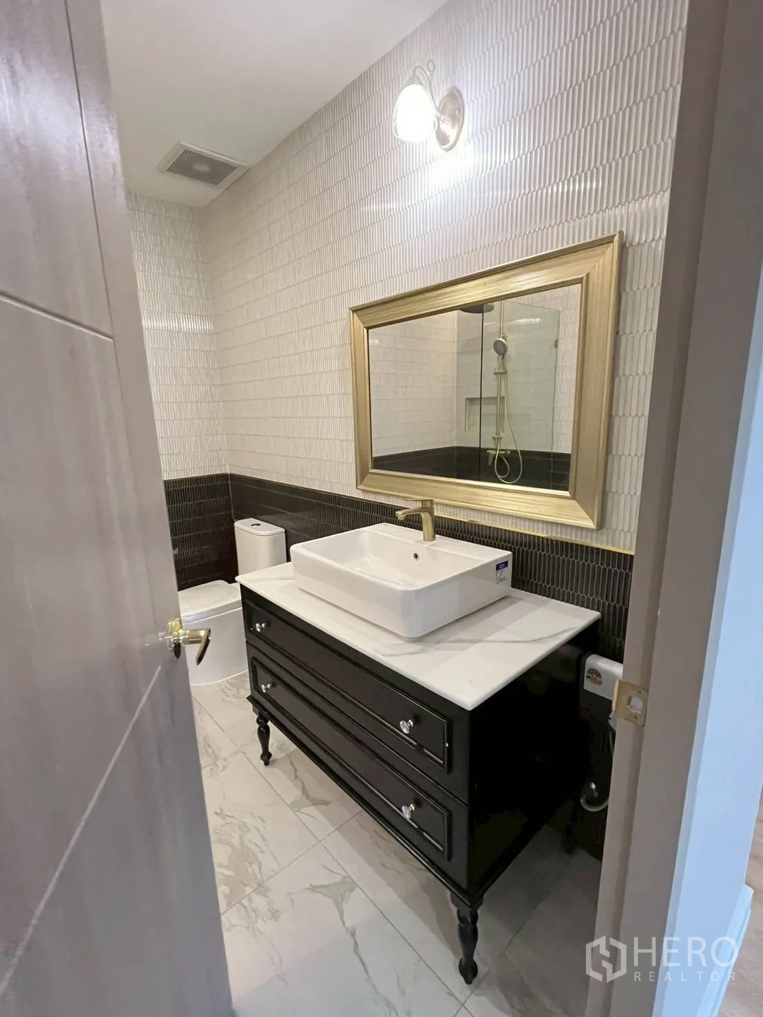 ทาวน์เฮาส์ for rent in Khlong Toei, Bangkok - ห้องน้ำขนาดกะทัดรัดพร้อมตู้ล้างหน้าสีดำ โคมไฟผนัง และพื้นกระเบื้อง.