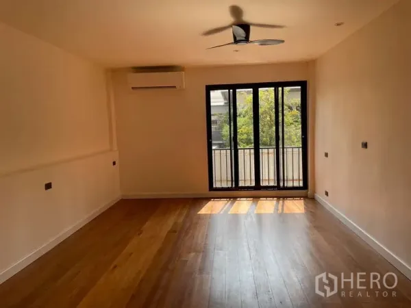 สำนักงานที่บ้าน ให้เช่าในWatthana, Bangkok - ห้องกว้างพร้อมประตูกระจกบานเลื่อนออกระเบียง พัดลมเพดานและพื้นไม้.