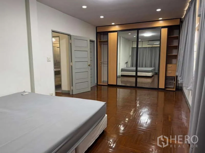 Detached House for rent in Bang Kapi, Bangkok - Spacious bedroom featuring mirrored wardrobe, wooden floors and door to en‑suite.
