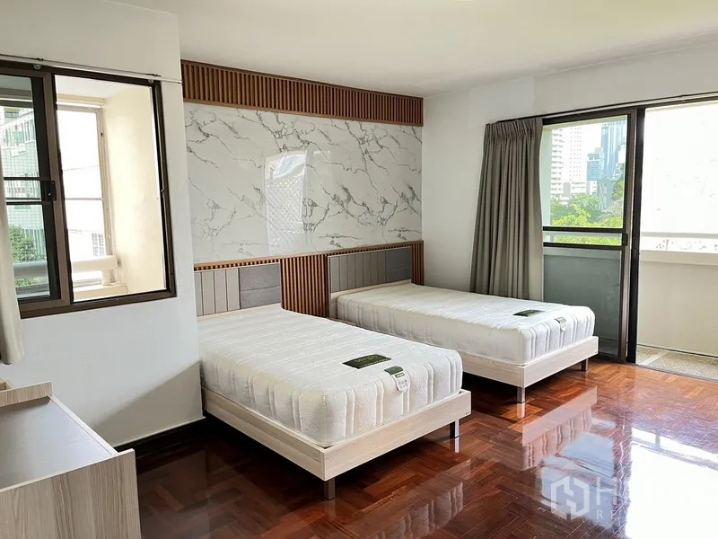 Condominium for rent in Watthana, Bangkok - Twin bedroom with marble accent headboard and sliding door to the balcony.