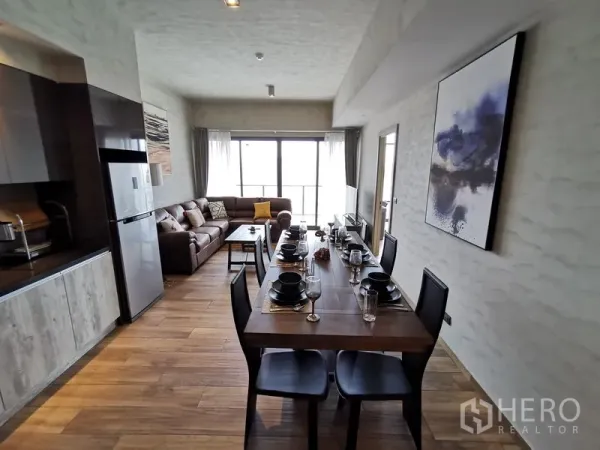 คอนโด ให้เช่าในWatthana, Bangkok - ครัวแบบเปิดติดกับโต๊ะอาหารสำหรับหกที่นั่ง เชื่อมสู่โซนรับแขกพร้อมโซฟาขนาดใหญ่และหน้าต่างกว้างแบบระเบียง