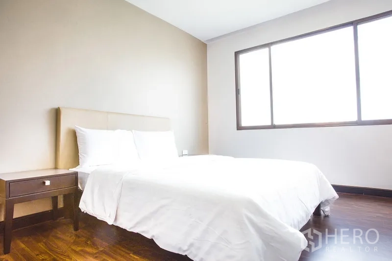 Condominium for rent in Watthana, Bangkok - Bright bedroom with white bedding and large window on wooden flooring.