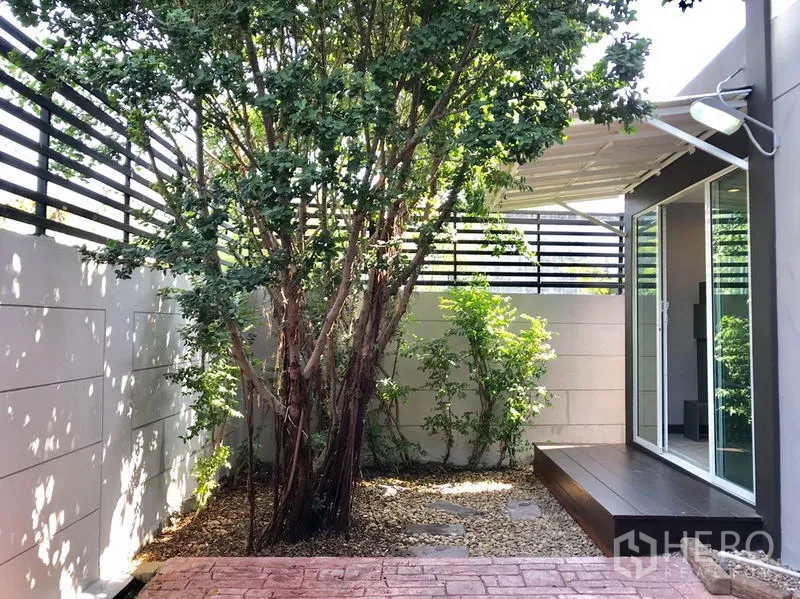Townhouse for rent or sale in Suan Luang, Bangkok - Private backyard with mature tree, small deck and sliding doors to the house.
