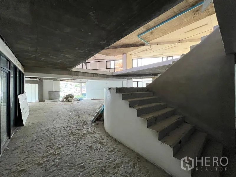 零售空间 出租在Watthana, Bangkok - 零售单元内的混凝土楼梯连接两层，窗边采光良好。