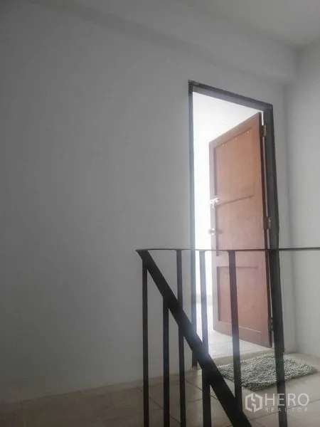 Shophouse for rent in Khlong Toei, Bangkok - Stair landing with black metal railing and wooden door.