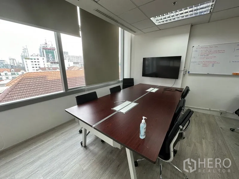 Office Space for rent in Khlong Toei, Bangkok - Meeting room with dark wood conference table, wall-mounted TV and whiteboard beside large city-view windows.