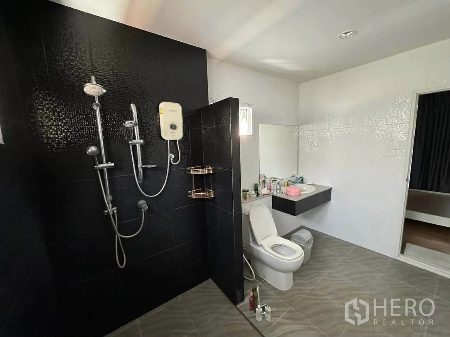 Detached House for rent in Watthana, Bangkok - Spacious bathroom with black tiled shower wall, electric water heater, toilet, and vanity.