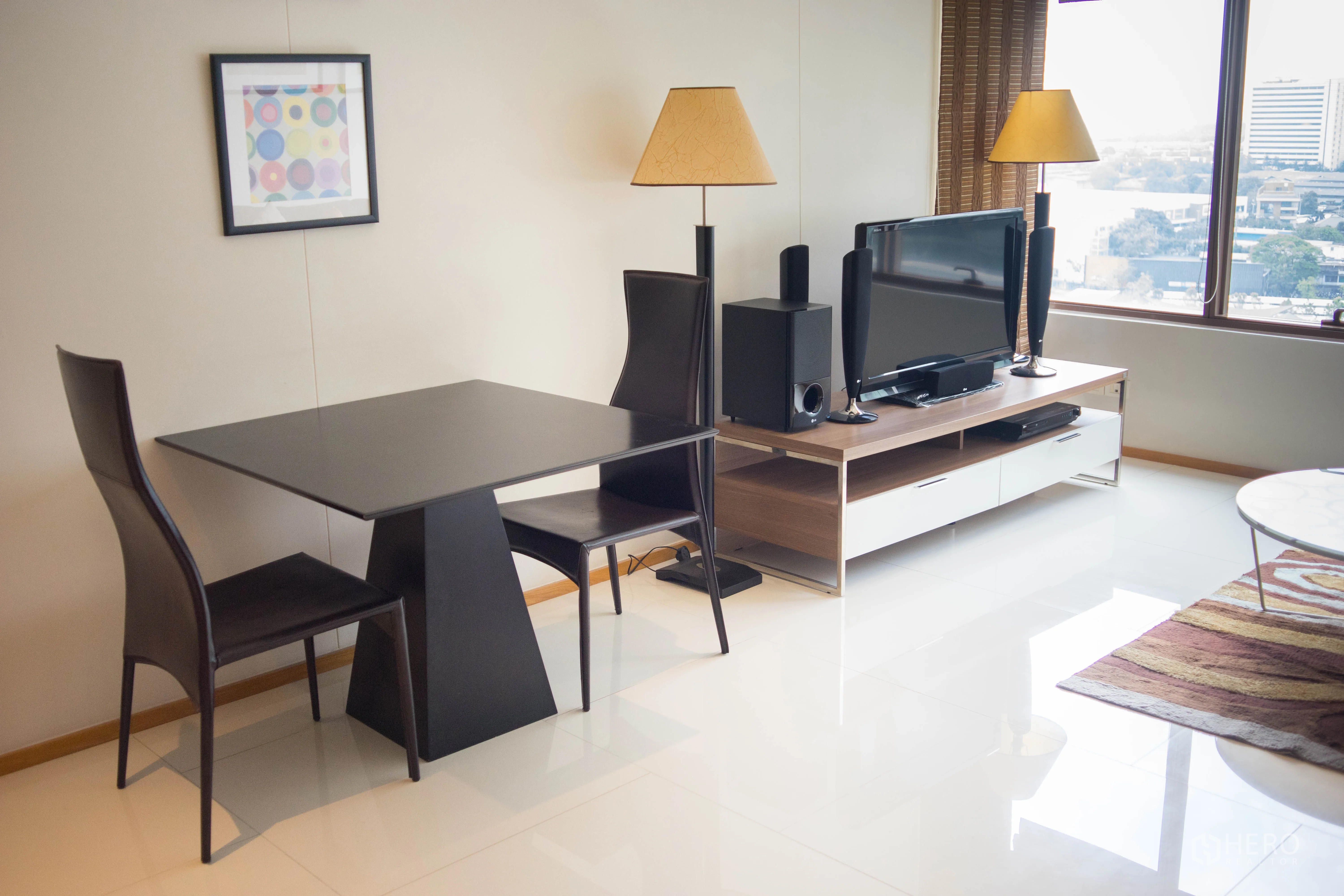 Condominium for rent or sale in Khlong Toei, Bangkok - Minimalist dining corner next to the living area with TV and large windows.