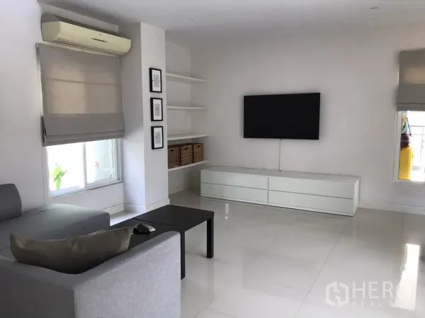 独立式住宅 出租或出售在Saphan Sung, Bangkok - 电视起居区，挂墙电视、内置置物架与大窗配百叶帘。