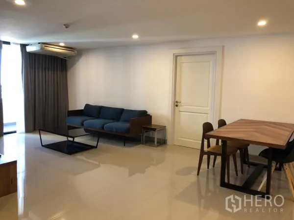 คอนโด ให้เช่าในWatthana, Bangkok - ห้องนั่งเล่นและรับประทานอาหารกว้าง โซฟาสีน้ำเงิน โต๊ะไม้ แอร์ และผ้าม่านสูงจรดพื้น