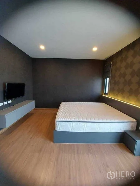 Detached House for rent in Bang Bo, Samut Prakan - Bedroom angle showing wall-mounted TV, low cabinet and king bed.