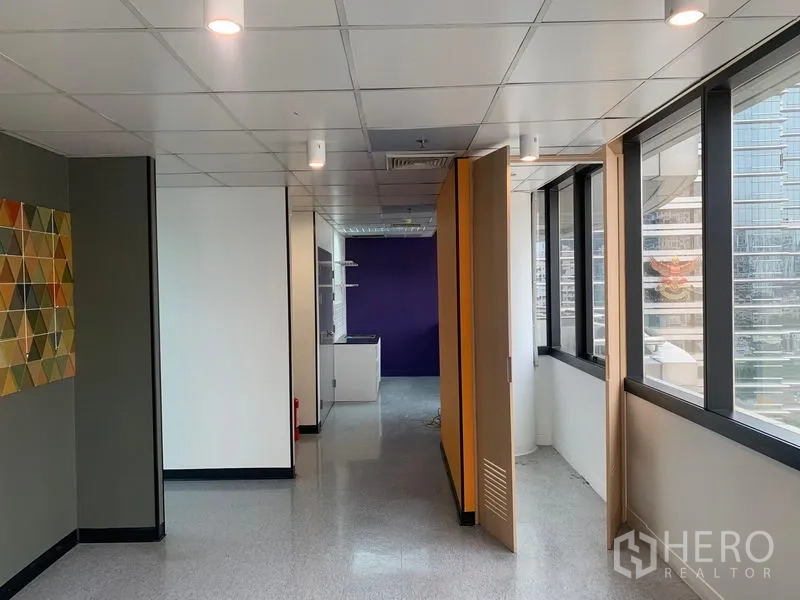 办公空间 出租在Bang Rak, Bangkok - 工作区域配折叠隔断、紫色强调墙及城市景观。