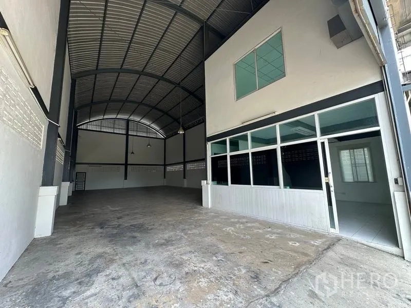 工厂 出租在Bang Bua Thong, Nonthaburi - 高挑弧形钢结构车间，混凝土地面，前方设有玻璃隔断办公室。