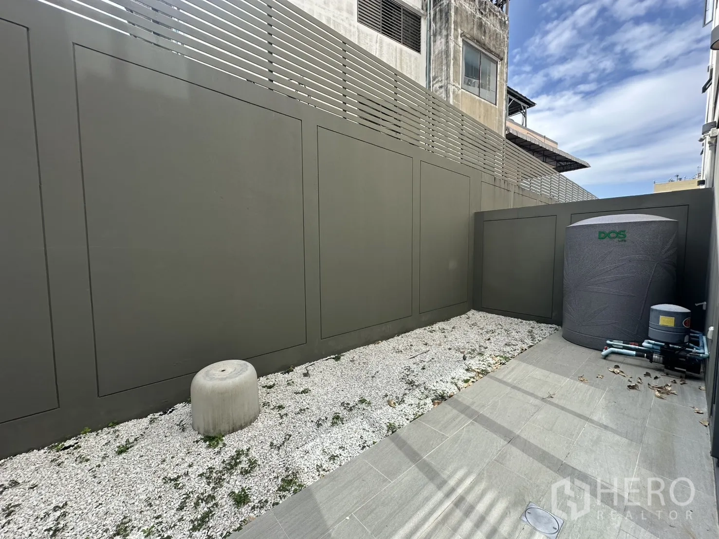 Home Office for rent or sale in Suan Luang, Bangkok - Service yard with water tank, pumps, and tiled path along the fence.