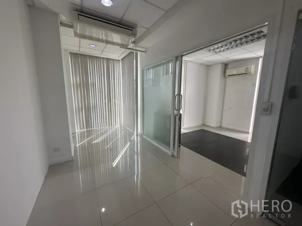 Office Space for rent in Huai Khwang, Bangkok - Hallway with sliding glass doors to private offices, vertical blinds and recessed lighting.