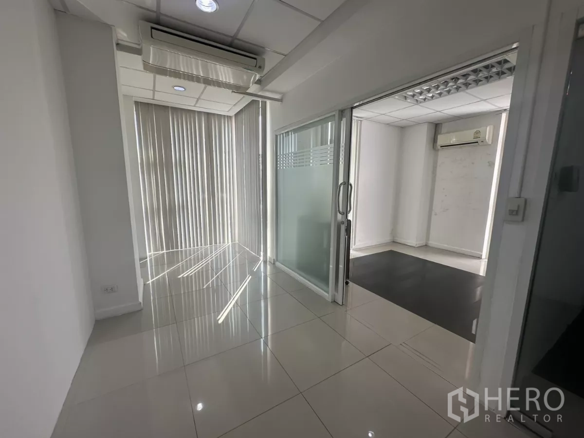 Office Space for rent in Huai Khwang, Bangkok - Hallway with sliding glass doors to private offices, vertical blinds and recessed lighting.