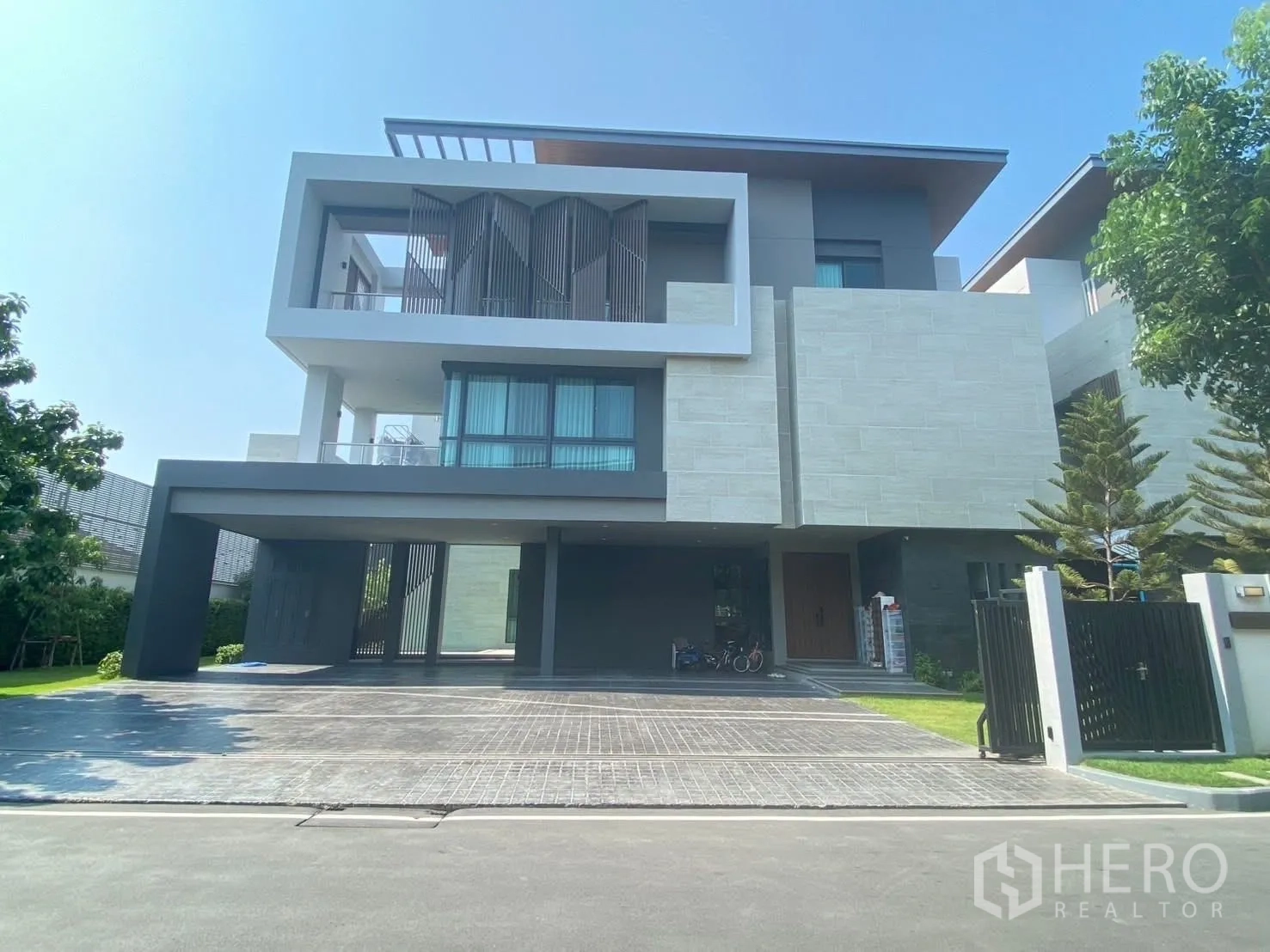 Detached House for rent or sale in Suan Luang, Bangkok - Front facade with wide driveway, gate and covered carport.