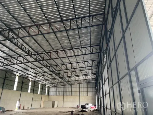 Warehouse for rent in Lam Luk Ka, Pathum Thani - Spacious warehouse interior showing steel trusses, insulated metal roof and concrete floor.