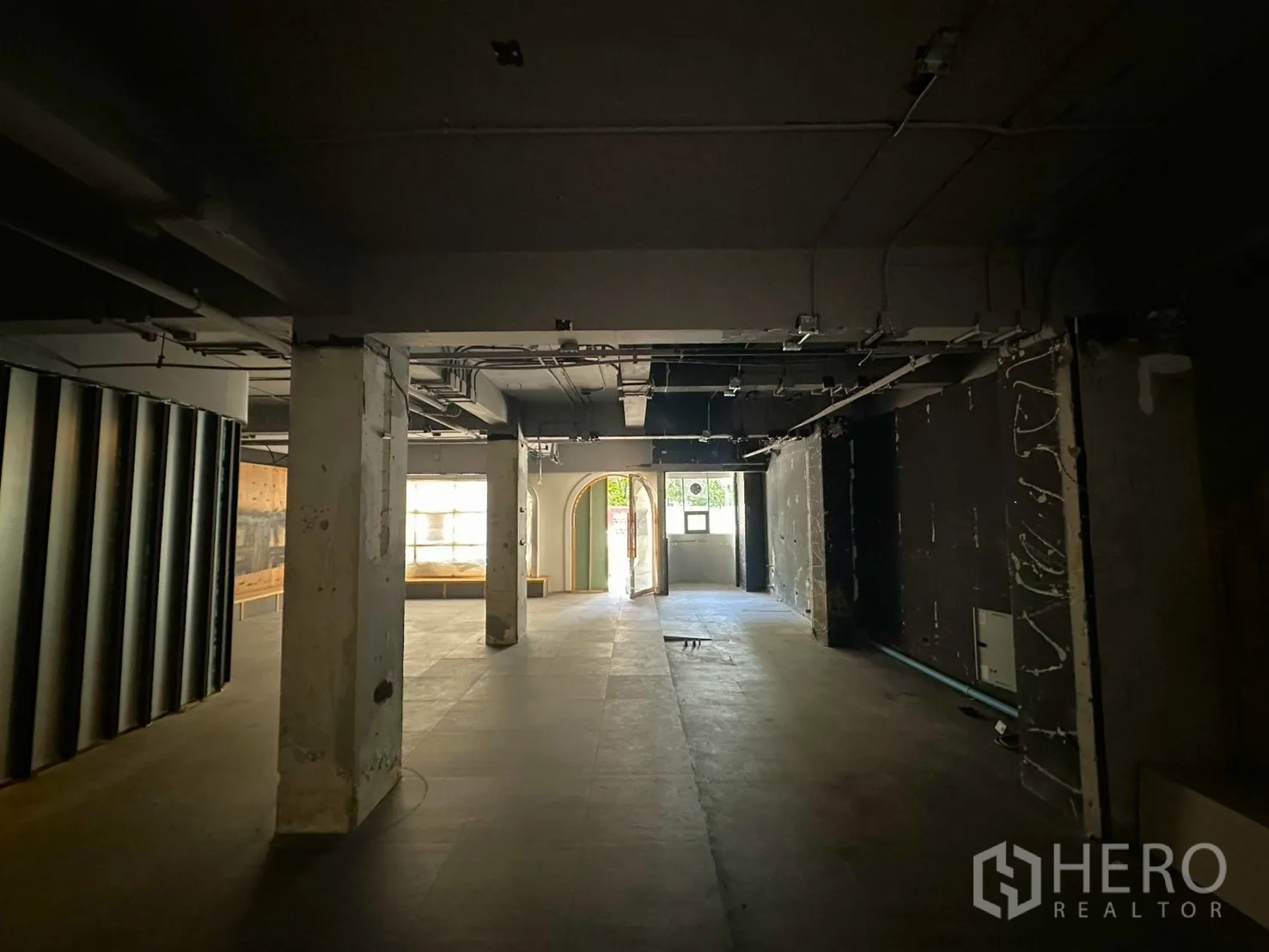 Retail Space for rent in Watthana, Bangkok - View from the back toward the entrance with columns, exposed ceiling, and a glass door.