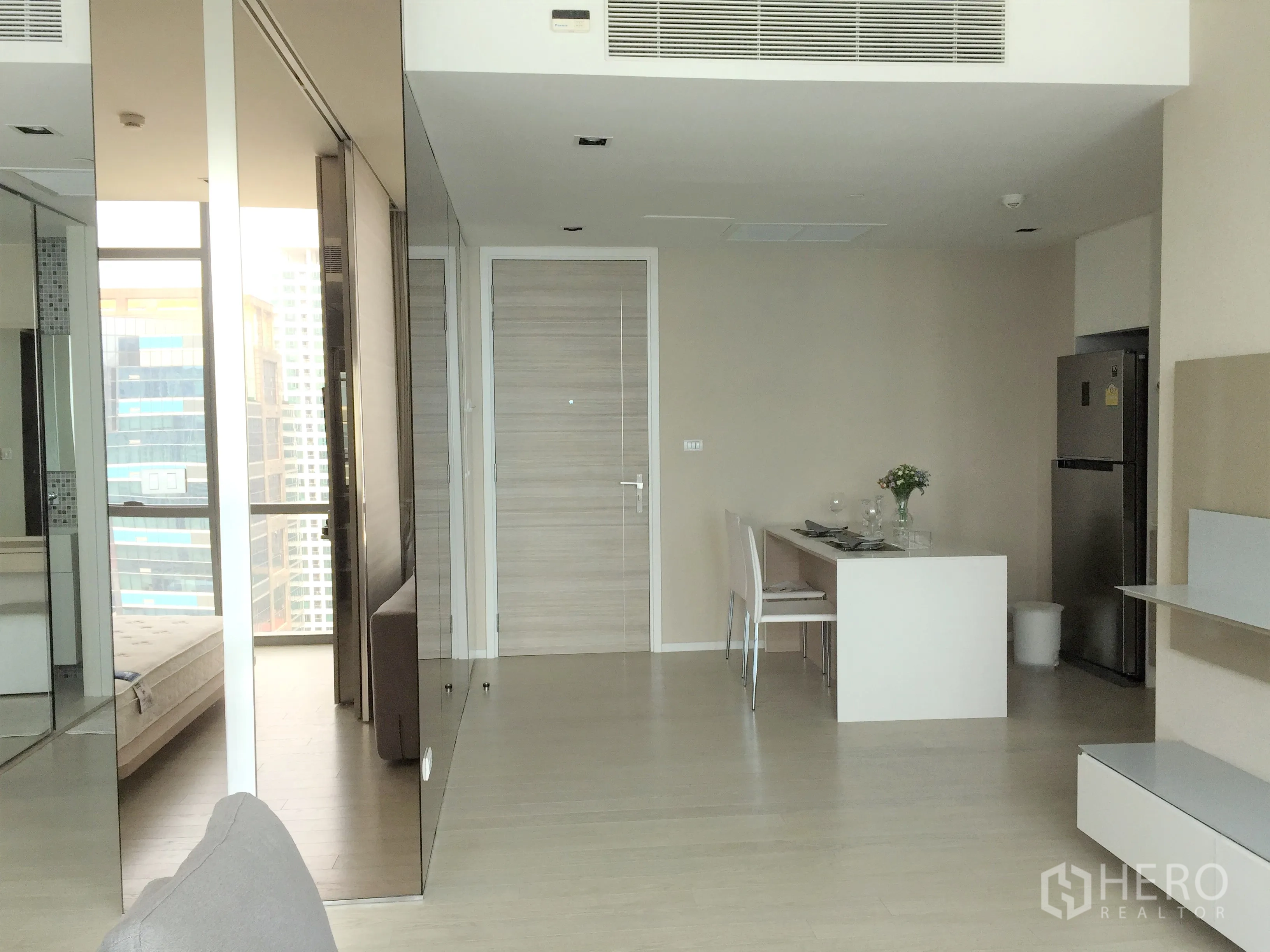 公寓 出租或出售在Watthana, Bangkok - 玄关与用餐区，白色中岛餐桌、内置收纳与通高镜面墙。
