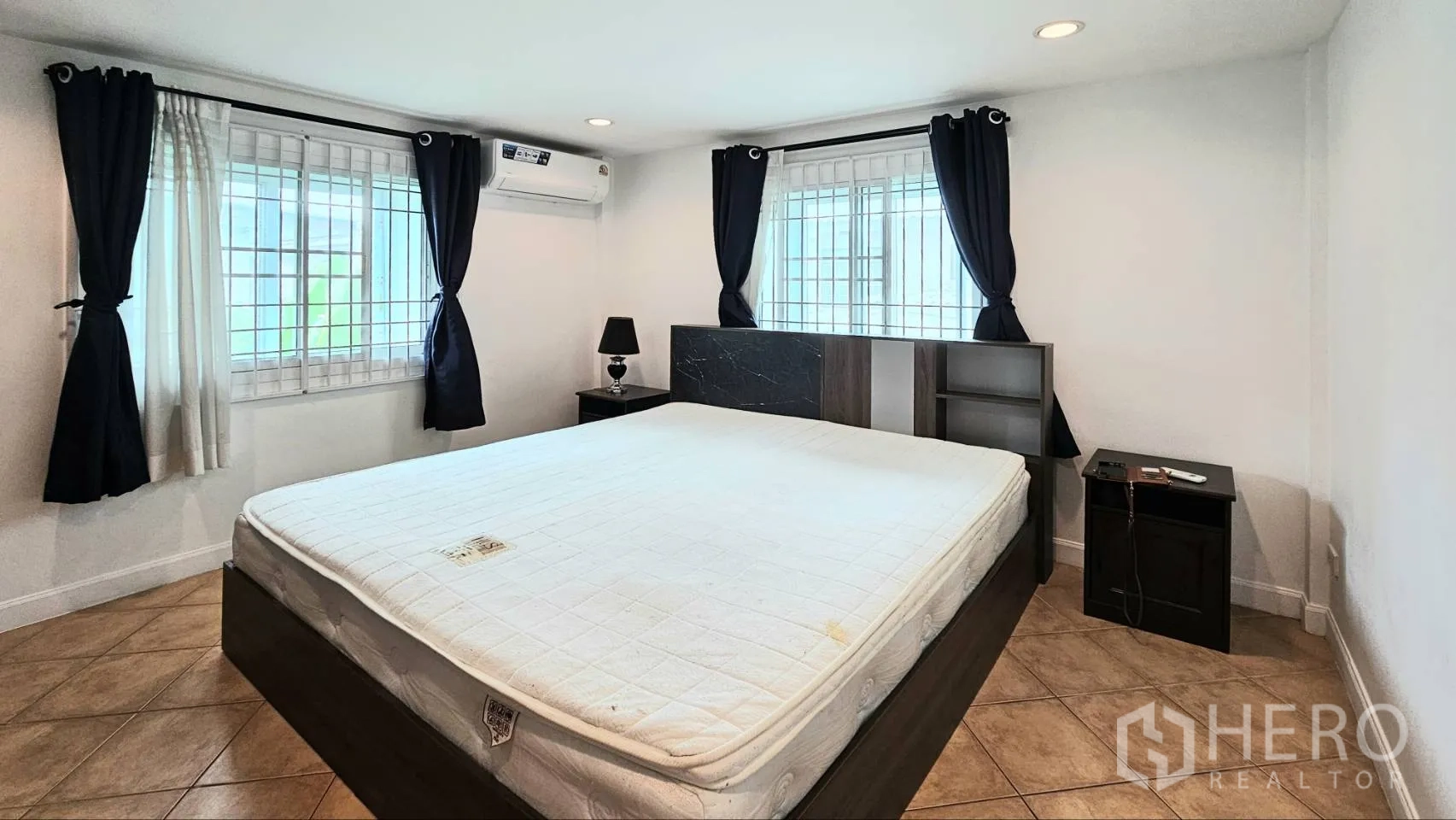 Detached House for rent in Saphan Sung, Bangkok - Master bedroom with large windows, blackout curtains, air conditioning, and bedside lamps.