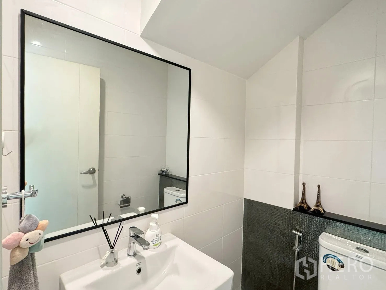 Townhouse for rent in Saphan Sung, Bangkok - Compact bathroom with sink, mirror and toilet under the stairs.