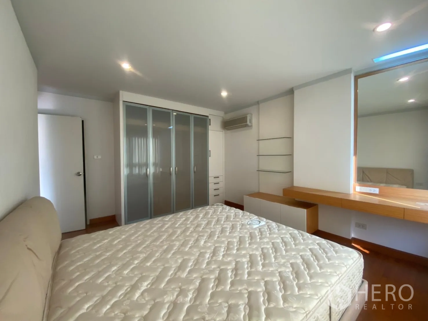Condominium for rent or sale in Sathon, Bangkok - Master bedroom angle showing glass-door wardrobe and air conditioning.