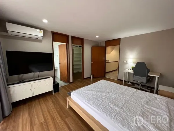 ทาวน์เฮาส์ ให้เช่าหรือขายในSuan Luang, Bangkok - ห้องนอนติดแอร์พร้อมเตียง ทีวี โต๊ะทำงาน และทางเข้าห้องน้ำ พื้นไม้โทนอุ่น